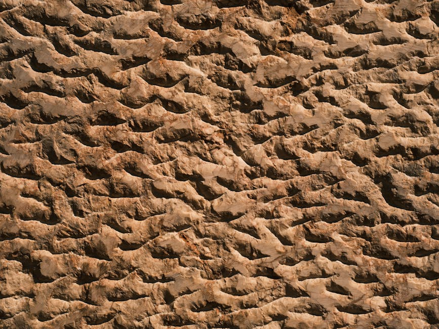 Hand führt Zahneisen über Sandsteinoberfläche beim Strukturieren